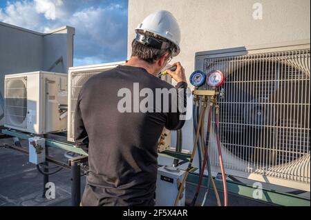 HVAC mechanic using a screw driver to tighten down power terminals to mini split air conditioner Stock Photo