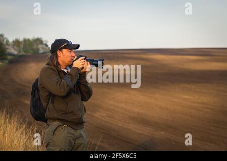 Photographing rural scene during golden hour. Man with camera outdoors. Photographer in Moravian Tuscany, countryside of Czech Republic Stock Photo