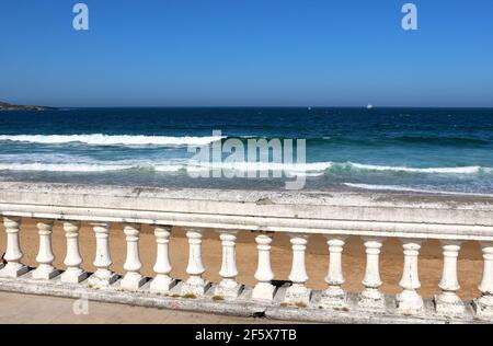 Deteriorating white balustrade fence in front of the beach in Sardinero Santander Cantabria Spain on a windy sunny spring afternoon Stock Photo