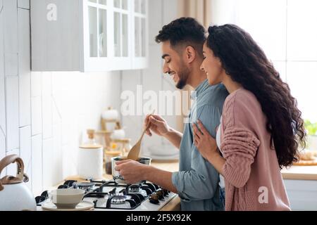 Couple Cooking Together Concept. Young arab spouses preparing dinner in kitchen Stock Photo