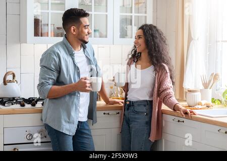 Portrait Of Happy Arab Couple Drinking Coffee And Chatting Together In Kitchen Stock Photo