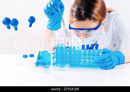 Female Research Scientist Uses Micropipette Filling Test Tubes.A laboratory assistant in a laboratory with test tubes produces vaccine samples. Develo Stock Photo