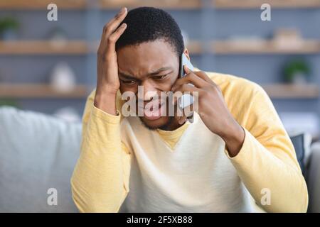 Closeup of sad black guy having conversation on phone Stock Photo