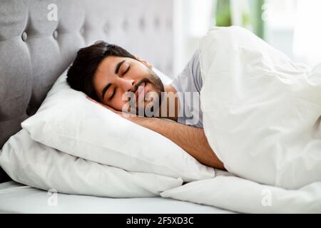 Just resting. Asleep arab man resting peacefully in his comfortable bed at home, having good dreams Stock Photo
