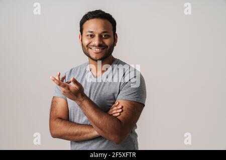 Asian unshaven happy man smiling and gesturing at camera isolated over gray background Stock Photo