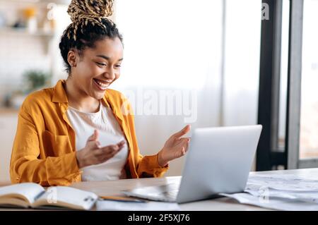 Online communication. Confident joyful beautiful african american young female student or freelancer with afro dreadlocks, study remotely, talks by online conference with coworkers or teacher, smile Stock Photo
