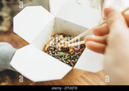 Close-up of noodles in a box. Takeaway food. Person eats food with chopsticks. Stock Photo