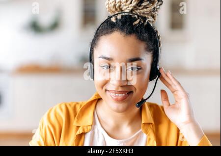 Close up portrait of a confident satisfied young african american woman wearing headphones, call center employee, freelance, assistant, communicating online, looking at camera, smiling friendly Stock Photo