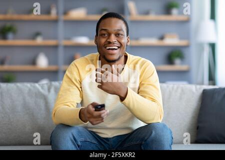 Laughing black guy watching comedy on TV at home Stock Photo
