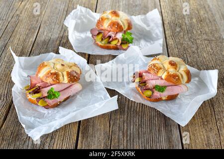 Bavarian street food, three pretzel roll sandwiches with smoked country ham and sliced pickles Stock Photo