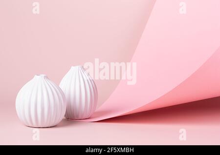 Spring romantic pastel pink abstract interior with white ceramic vases and flying folded paper. Concept in minimalist style with geometric composition Stock Photo
