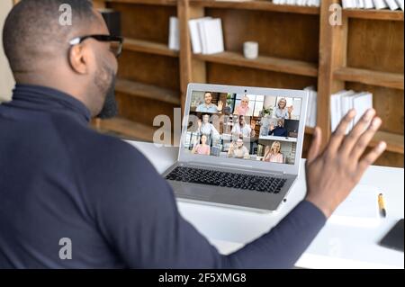 Back view of african businessman talk with co-workers partners using video call on laptop, discuss work project online, talking with clients, speak on webcam conference on computer, greeting Stock Photo