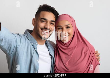 Cheerful Young Muslim Couple Taking Selfie Together, Happy Spouses Smiling At Camera Stock Photo