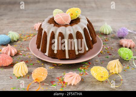 Glazed easter cake decorated with mini eggs candy on wooden table. Happy Easter Holidays. Stock Photo