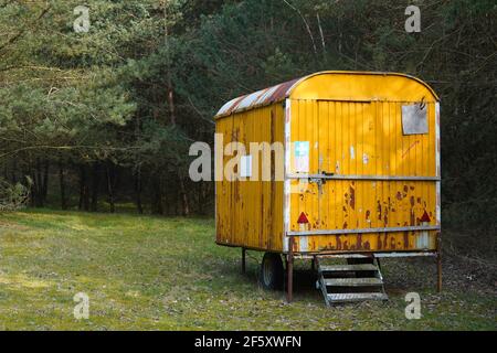 Old yellow rusty construction camper, trailer, van or wagon in the forest. Temporary housing for forest workers . Stock Photo