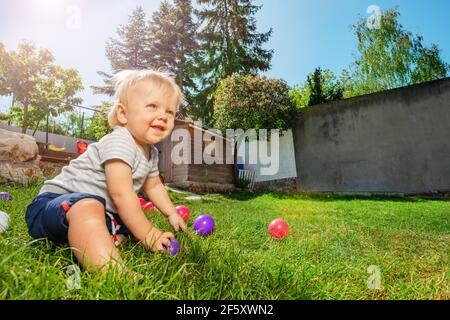 Toddler blond boy play with balls on the grass Stock Photo