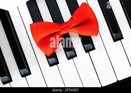 Red bow tie on piano keyboard.  Closeup Stock Photo