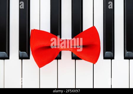 Red bow tie on piano keyboard. Vintage style. Closeup Stock Photo