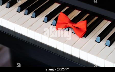Red bow tie on piano keyboard. Closeup Stock Photo