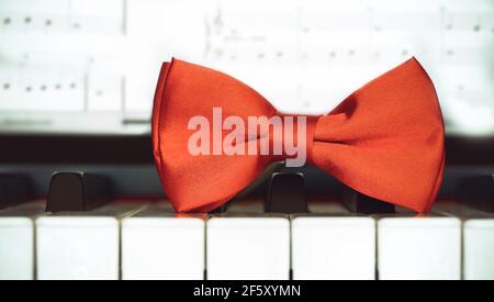 Red bow tie on piano keyboard. Vintage style. Closeup Stock Photo