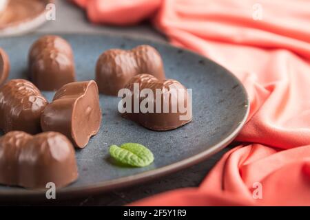 Chocolate candies with almonds and a cup of coffee on a black concrete background and red textile. Side view, close up, selective focus. Stock Photo
