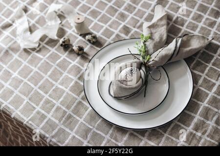 Spring breakfast still life. Easter decoration table setting. Greeting card mockup, quail and hen eggs. Plates, napkin folding decoration on blurred Stock Photo