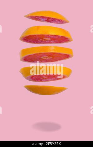 Floating levitating ripe grapefruit on pink background. Vitamins, healthy diet concept. Minimal fruit idea. Sliced grapefruit floating in the air. Cre Stock Photo