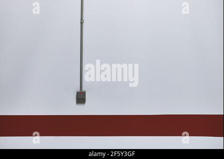 detail of a light switch on a white wall with a red stripe in a parking garage Stock Photo