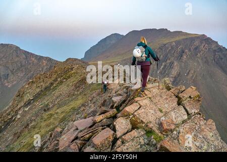 Rear view of female hiker with hiking poles on rocks at mountain Stock Photo