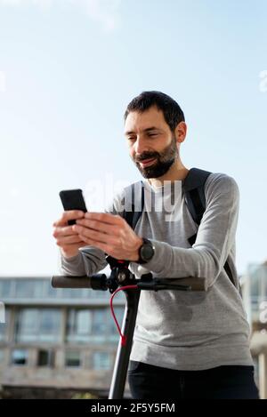 Young man standing on scooter and using smartphone Stock Photo