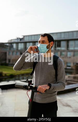 Young man standing on scooter and using smartphone Stock Photo
