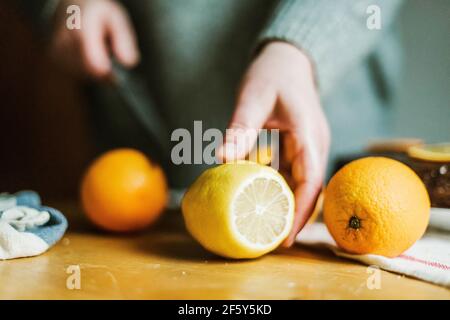 Anonymous woman in her kitchen at home slicing oranges with a sh Stock Photo