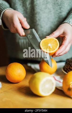 Anonymous woman in her kitchen at home slicing oranges with a sh Stock Photo