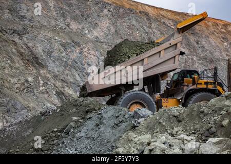 Rudny/Kazakhstan - May 14 2012:  Open-pit mining iron ore in quarry. Caterpillar quarry truck dumping car. Stock Photo