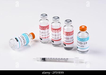 Two different types of Covid-19 Vaccines on white with a syringe in the foreground. Stock Photo
