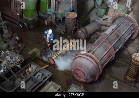 Rudny, Kostanay region, Kazakhstan-May 28 2012: Sokolovo-Sarbay Mining and processing plant. Worker cleaning heat exchanger filter with hot water on e Stock Photo