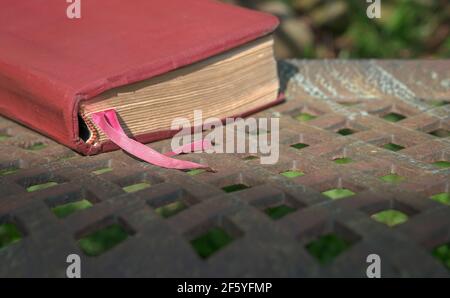 Red brown leather cover book with bookmark ribbon on a steel bench. Copy space. Stock Photo