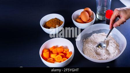 Hand of a man making homemade carrot muffins on a dark surface Stock Photo