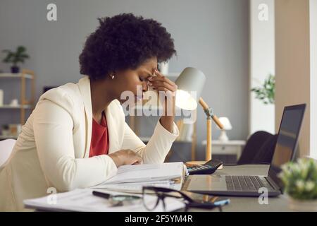 Frustrated african american woman keeping eyes closed and massaging nose Stock Photo