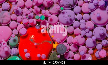 Ink bubbles mixed with liquid substance of oil, milk, soap, bright acrylic paint on colorful surface Stock Photo