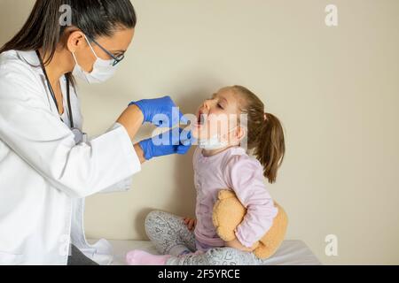 chubby little girl in pediatric examination by her doctor. ENT ( Ear, Nose, Throat ) Examination. Selective Focus Stock Photo