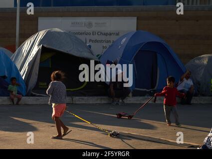 Tijuana, Mexico. 27th Mar, 2021. Children are playing with toys in front of tents. Migrants from Central America are stuck living in tents on the street in Tijuana, Mexico on the border while they wait for President Joe Biden to open the American border. Credit: Allison Dinner/ZUMA Wire/Alamy Live News Stock Photo