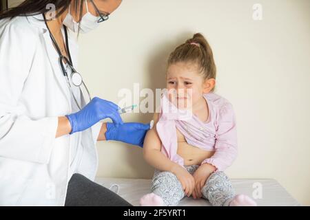 chubby little girl in pediatric examination by her doctor. vaccinated by her doctor. Selective Focus. covid vaccine baby Stock Photo