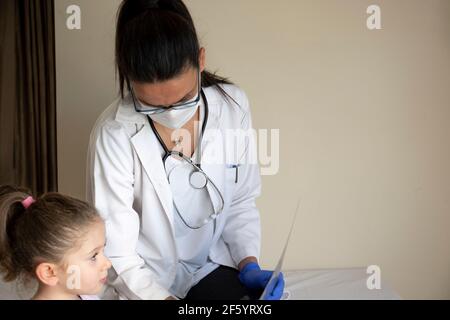 chubby little girl in pediatric examination by her doctor. They are looking x-ray film. copy space, space for text. Selective Focus Stock Photo