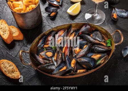 Moules frites, mussels with fries, with lemon and toasts Stock Photo