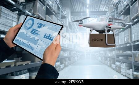 Warehouse manager with digital tablet controls drone with a package. Unmanned delivery concept Stock Photo