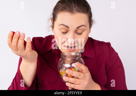 Close-up portrait of plus size nice attractive charming sweet cute cheerful cheery dreamy plump woman smelling sweet candies in opened glass jar Stock Photo