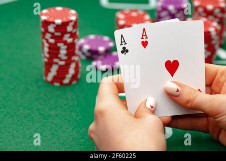 Female holding playing cards, playing poker at green table Stock Photo