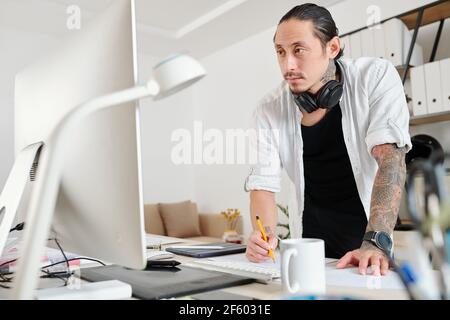 Pensive designer reading e-mail from client when drawing logotype for a big company Stock Photo