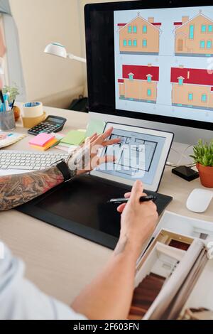 Hands of interior designer checking construction plan of house when working on graphic tablet at his desk Stock Photo